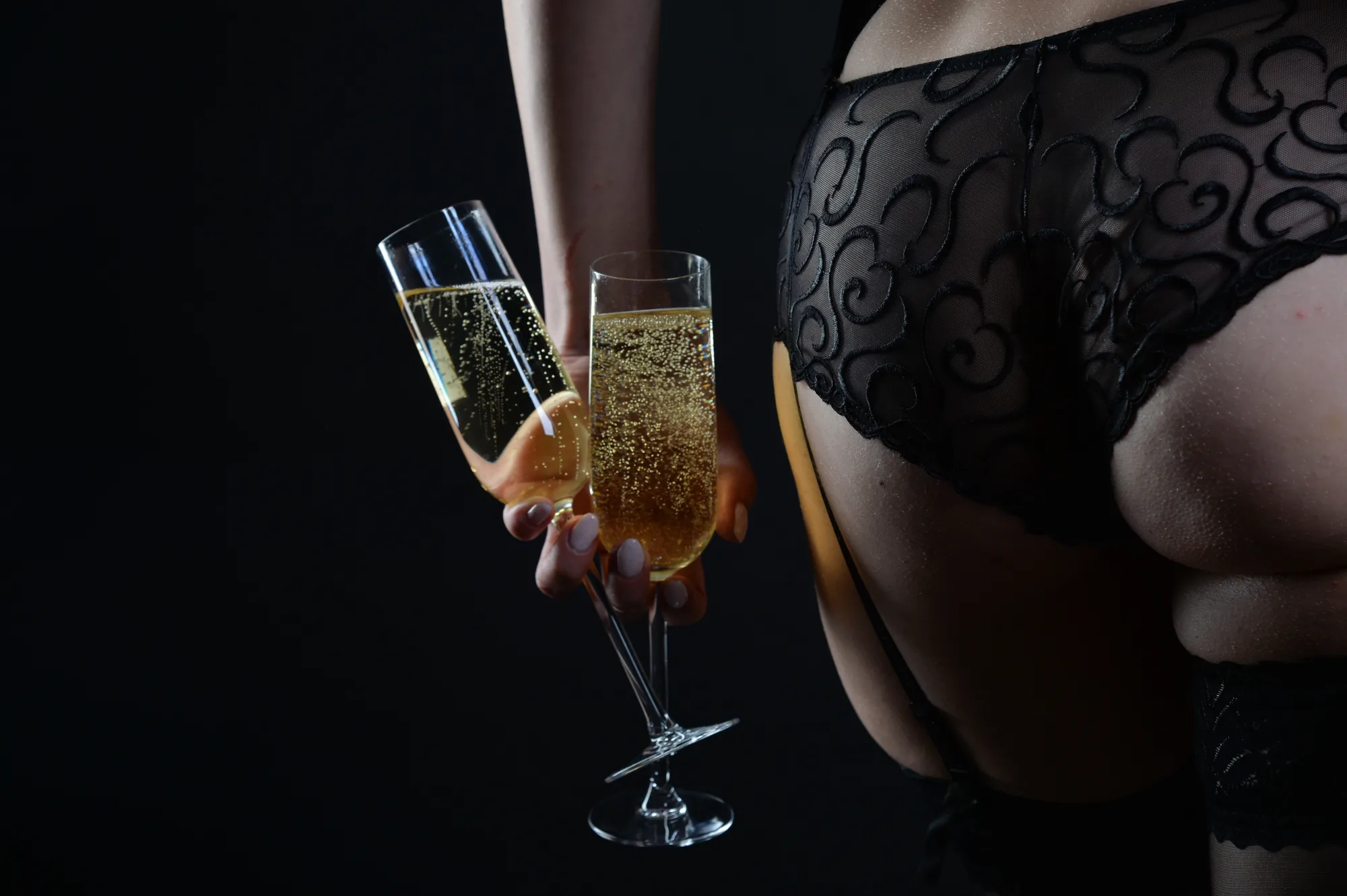 Champagne & sweet seduction: two glasses of champagne in hand, lingerie and suspenders beside them